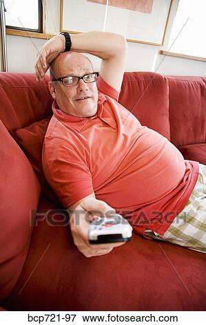 Man watching television on sofa View Large Photo Image Stock Photo - Man watching television on sofa. Fotosearch