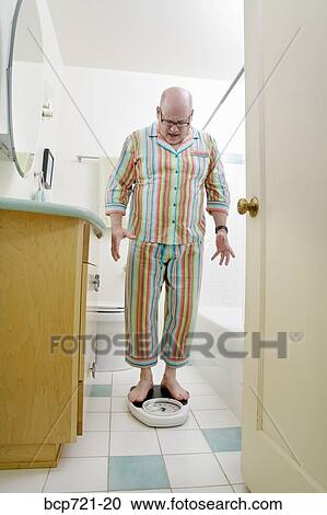 Man weighing himself in bathroom View Large Photo Image Stock Image - Man weighing himself in bathroom. Fotosearch