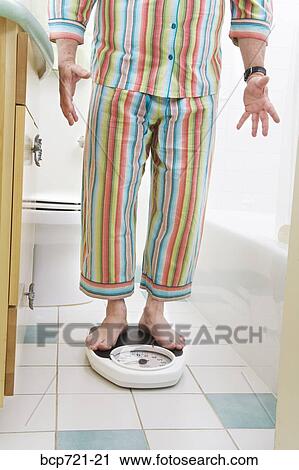 Man weighing himself in bathroom View Large Photo Image Stock Image - Man weighing himself in bathroom. Fotosearch