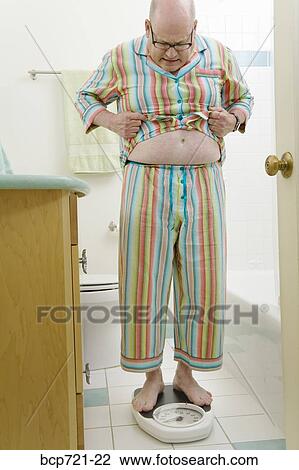 Man weighing himself in bathroom View Large Photo Image Stock Image - Man weighing himself in bathroom. Fotosearch