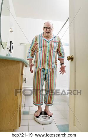 Man weighing himself in bathroom View Large Photo Image Stock Photo - Man weighing himself in bathroom. Fotosearch