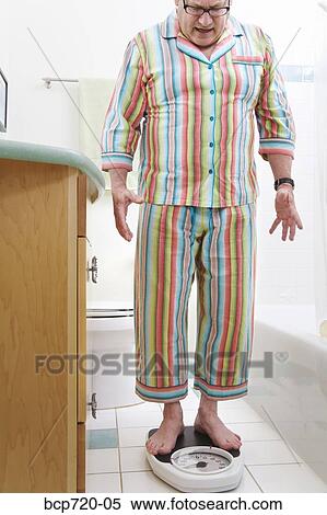 Man weighing himself in bathroom View Large Photo Image Stock Photography - Man weighing himself in bathroom. Fotosearch