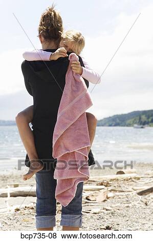 Stock Photo - Mother hugging daughter at beach. Fotosearch