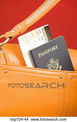 Picture - Passport sticking out of orange purse. Fotosearch