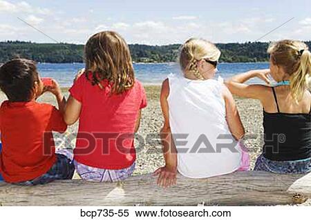 Stock Photography - Rear view of children sitting on log. Fotosearch