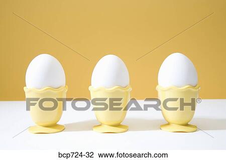 Stock Image - Row of eggs in egg cups. Fotosearch