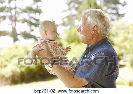 Stock Image - Senior man holding baby. Fotosearch