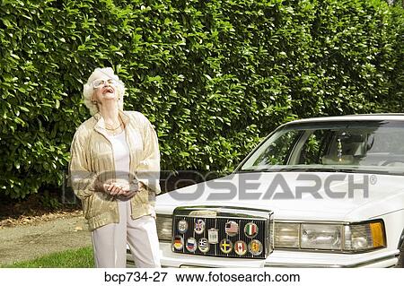 Senior woman laughing next to car View Large Photo Image Stock Photo - Senior woman laughing next to car. Fotosearch