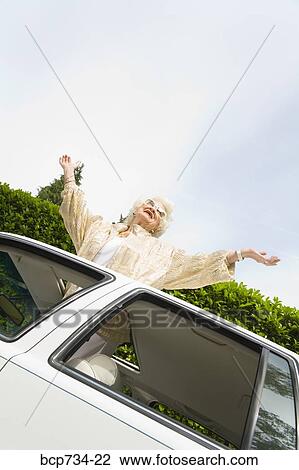 Senior woman standing in sunroof of car View Large Photo Image Stock Image - Senior woman standing in sunroof of car. Fotosearch