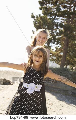 Stock Photo - Sisters in party dresses outdoors. Fotosearch
