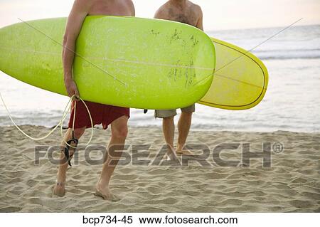 Stock Photography - Two men carrying surfboards. Fotosearch