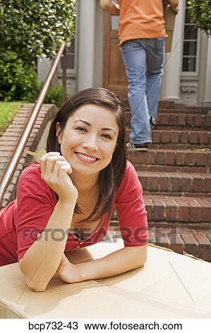 Woman holding key in front of new house View Large Photo Image Stock Image - Woman holding key in front of new house. Fotosearch