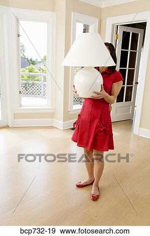 Woman holding lamp in new house View Large Photo Image Stock Photo - Woman holding lamp in new house. Fotosearch