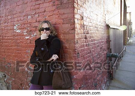 Woman leaning against brick wall, Woman standing on urban street corner, New York City View Large Photo Image Stock Image - Woman leaning against brick wall, Woman standing on urban street corner, New York City. Fotosearch