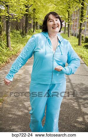 Picture - Woman power walking outdoors. Fotosearch