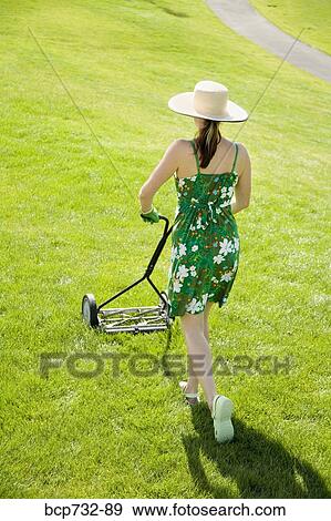 Stock Photo - Woman pushing lawn mower. Fotosearch