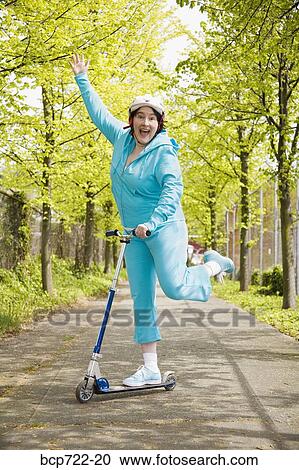 Woman riding a scooter View Large Photo Image Stock Image - Woman riding a scooter. Fotosearch
