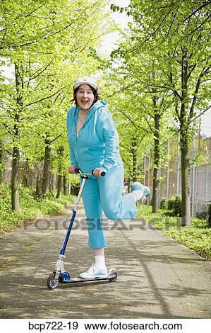 Woman riding a scooter View Large Photo Image Stock Photo - Woman riding a scooter. Fotosearch