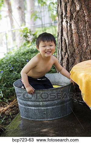 Stock Image - Young boy sitting in wash tub. Fotosearch