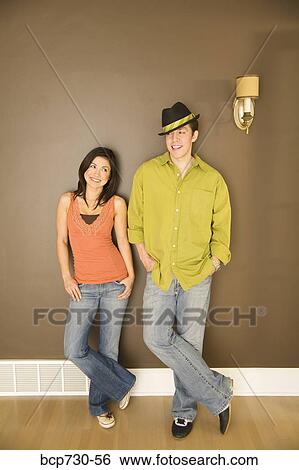Young couple leaning on wall View Large Photo Image Stock Photograph - Young couple leaning on wall. Fotosearch