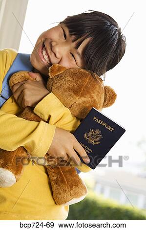 Stock Photo - Young girl holding teddy bear and passport. Fotosearch