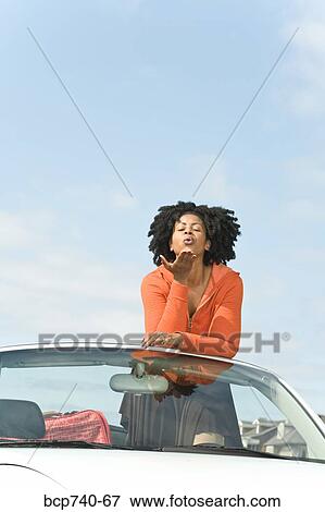 African woman blowing kiss in convertible car View Large Photo Image Stock Photo - African woman blowing kiss in convertible car. Fotosearch