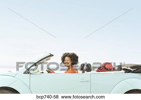 Stock Photo - African woman driving convertible car. Fotosearch