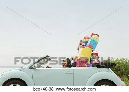 Stock Photo - African woman in convertible with shopping bags. Fotosearch