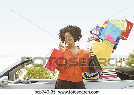 Stock Photography - African woman next to car filled with shopping bags. Fotosearch