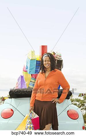 African woman next to convertible with shopping bags View Large Photo Image Stock Photo - African woman next to convertible with shopping bags. Fotosearch