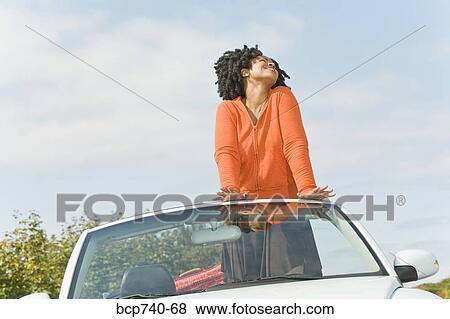African woman standing in convertible car View Large Photo Image Stock Photo - African woman standing in convertible car. Fotosearch