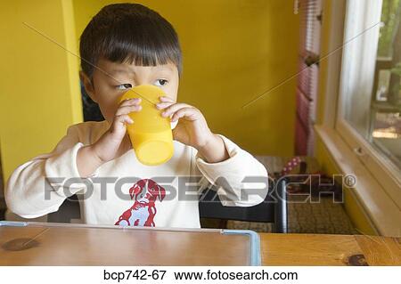 Stock Photo - Asian boy drinking from cup. Fotosearch