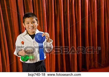Asian boy holding prize ribbon on stage View Large Photo Image Stock Photo - Asian boy holding prize ribbon on stage. Fotosearch