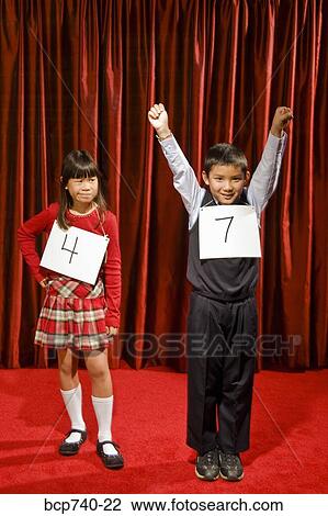 Stock Image - Asian boy wearing number and cheering on stage. Fotosearch
