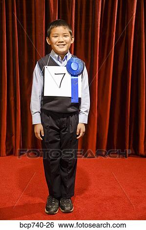 Stock Photograph - Asian boy wearing prize ribbon on stage. Fotosearch