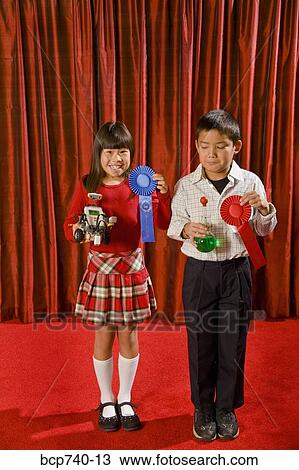 Asian girl and boy holding prize ribbons on stage View Large Photo Image Stock Image - Asian girl and boy holding prize ribbons on stage. Fotosearch