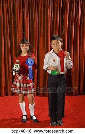 Asian girl and boy holding prize ribbons on stage View Large Photo Image Stock Photograph - Asian girl and boy holding prize ribbons on stage. Fotosearch