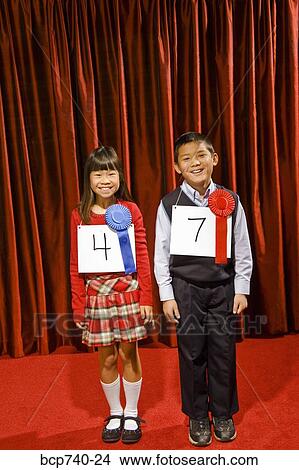 Asian girl and boy wearing prize ribbons on stage View Large Photo Image Picture - Asian girl and boy wearing prize ribbons on stage. Fotosearch