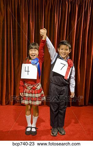 Asian girl and boy wearing prize ribbons on stage View Large Photo Image Stock Image - Asian girl and boy wearing prize ribbons on stage. Fotosearch