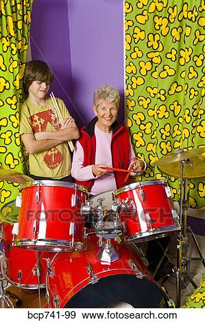 Stock Photo - Boy showing grandmother how to play drums. Fotosearch