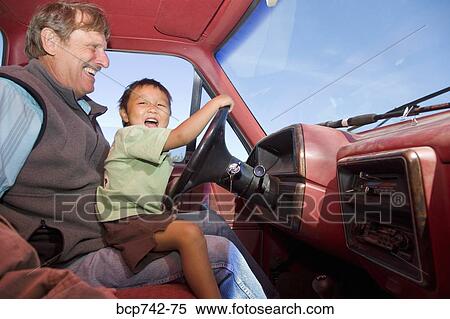 Stock Photography - Grandfather with grandson on lap in car. Fotosearch