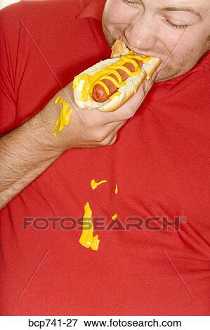 Man eating hotdog and spilling mustard on shirt View Large Photo Image Stock Photo - Man eating hotdog and spilling mustard on shirt. Fotosearch