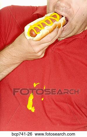 Man eating hotdog and spilling mustard on shirt View Large Photo Image Stock Photograph - Man eating hotdog and spilling mustard on shirt. Fotosearch