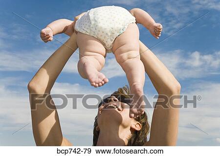 Stock Photo - Mother holding baby up in air. Fotosearch