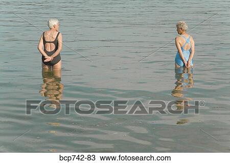 Stock Image - Senior women standing in water. Fotosearch