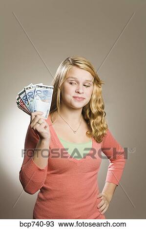 Stock Image - Teenage girl holding fanned out money. Fotosearch