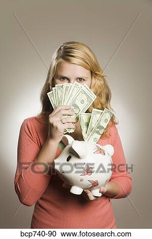 Teenage girl holding money and piggy bank View Large Photo Image Stock Image - Teenage girl holding money and piggy bank. Fotosearch