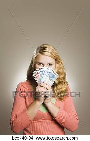 Picture - Teenage girl holding money in front of face. Fotosearch