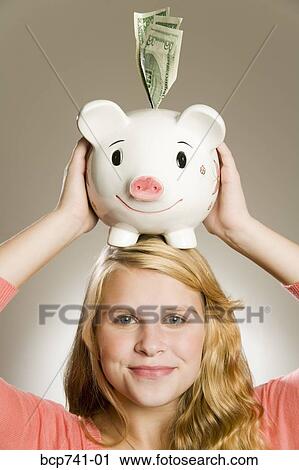 Teenage girl holding piggy bank on head View Large Photo Image Stock Image - Teenage girl holding piggy bank on head. Fotosearch