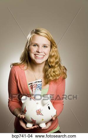 Teenage girl holding piggy bank with money View Large Photo Image Picture - Teenage girl holding piggy bank with money. Fotosearch
